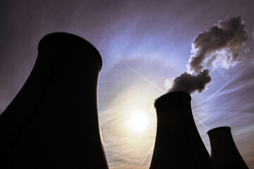 Silhouettes of cooling towers with the sun in the background