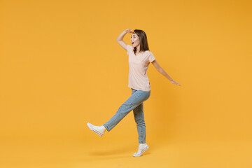 Fototapeta na wymiar Full length side view portrait of shocked amazed young woman wearing pastel pink casual t-shirt posing holding hand at forehead looking far away distance isolated on yellow color background studio.