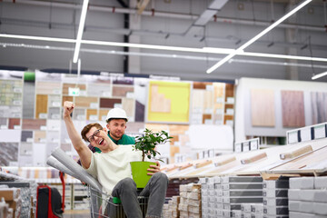 joyful customer and warehouse worker have fun in the store, young men going crazy after shopping,...