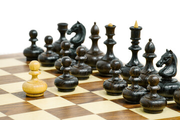 One of white chess pawn attacks black chess piecec army. Wooden chess pieces on the board. Chess game position.