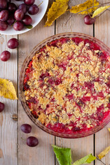 Plum pie with crumble on wooden table