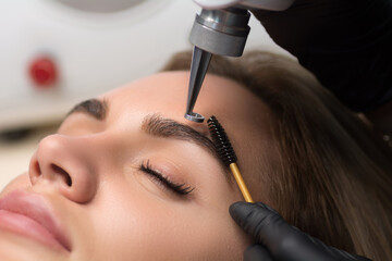 Laser removal of permanent makeup. The beautician removes the tattoo from the eyebrows.