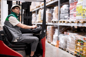 professional warehouse worker sit inside of machine, doing logistics, check