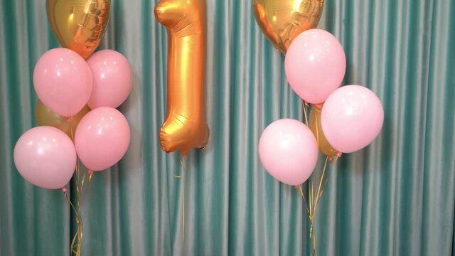 decor of pink and gold balloons and the number 1 for the baby's birthday.