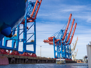 next to a container ship there are large container cranes for loading and unloading the ships