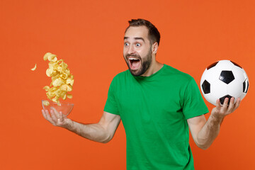 Shocked young man football fan in green t-shirt cheer up support favorite team with soccer ball...