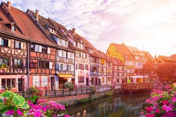 Fototapeta na wymiar Sunset in Colmar. Famous landmark, romantic village with multicolor half-timbered houses by the bank of canal, unrecognizable people. Summertime, Alsace France.