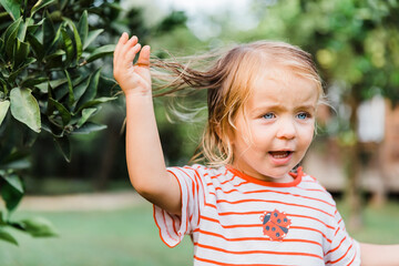Toddler girl with hand in hair outdoors
