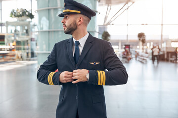 Handsome male pilot buttoning up his jacket © Svitlana