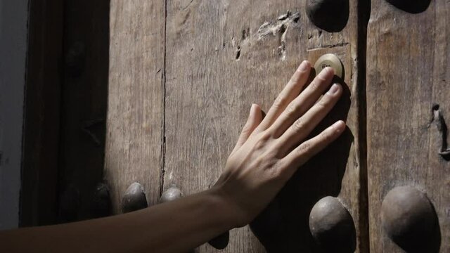 Mano de mujer blanca joven acariciando una puerta de madera antigua HD