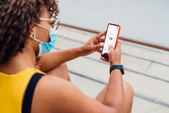 African american woman using running app while using a protective mask during coronavirus outbreak - Focus on phone