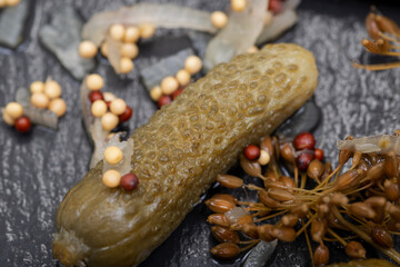 Extra Fine Cornichons - minuscule sour French pickles on natural stone background. Mini French style Gherkin Cucumbers.