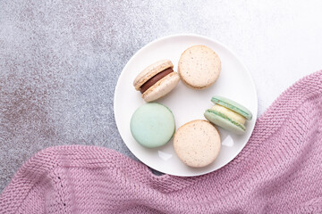 Wool plaid and macaroons on stone background. Cozy autumn composition. Flat lay, top view