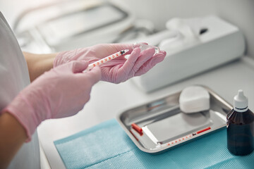 Female hands holding syringe and ampule with solution