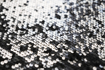Sequin fabric texture. Shiny silver sparkling background. Clothing piece of glitter metallic for a glamorous party, celebration. Close-up.