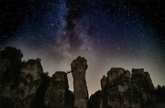 impressive starry night sky with visible milky way over the rocks called "Externsteine" in the region "Teutoburger Wald" (Germany) at september 20th, 2020