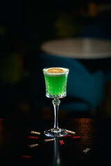 alcoholic cocktail green in a glass with lemon on a black background in a bar restaurant
