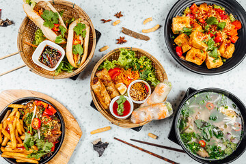 Fresh and delicius Vietnamese food table, Pho ga, pho bowls, noodles, spring rolls, asian dinner table on bright background