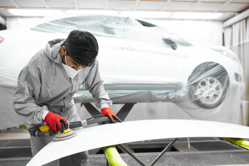 car, auto detailing. young auto mechanic man work with the use of orbital polisher, in auto repair...