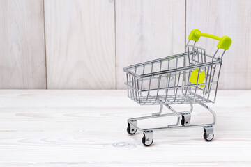 Empty shopping cart on white wooden background.