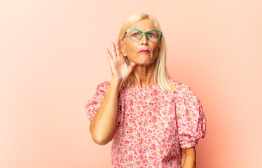 middle age woman looking serious and curious, listening, trying to hear a secret conversation or...