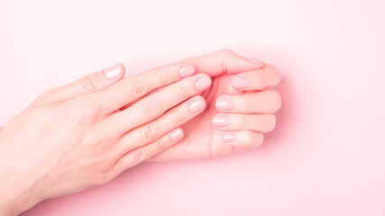 Beautiful female hands showing fresh cute manicure, skin and nail care concept, pink background