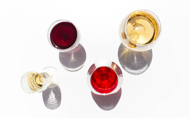 glasses of red and white wine on white background with sparkling shadows. Free copy space.  Concept of organic drinks. Top view.
