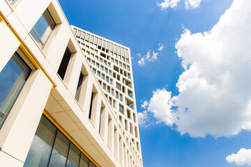 office building exterior outdoor facade architecture side landmark photography foreshortening from below on vivid blue sky white clouds background