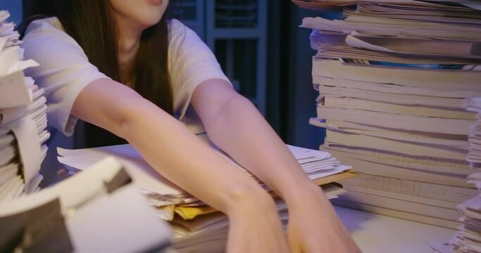 Young asian student woman dropping document on desk cover with stack of paperwork. Alone teen girl exhausted, tired and and lay down on pile of paper sheet while studying hard at late night.