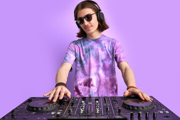 caucasian stylish dj man in sunglasses mixing console on purple studio background, perform dance...
