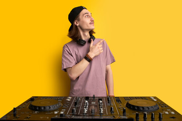 disco man make party music, looks away behind console, posing at camera isolated over yellow...