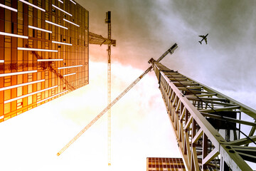 Tower crane. Bottom view of a tall construction cranes next to a modern building. Engineering and...