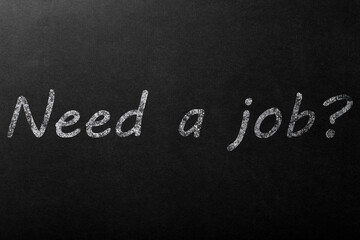 The inscription "need a job?" in white chalk on a dark blackboard.