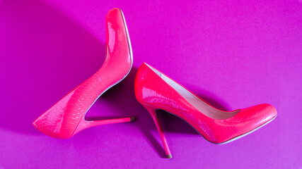 Elegant classic shoes close-up. Bright pink high heeled shoes. Pink and violet background.