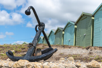 Photo of the anchor at Charmouth beach with beach huts in the background