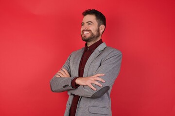 Young caucasian businessman wearing casual clothes standing over isolated red background crossing...
