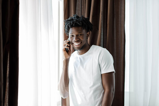 Overjoyed african American millennial man laugh having pleasant cellphone conversation, happy biracial male smile involved in smartphone call, talking using modern gadget, good connection concept. - Powered by Adobe