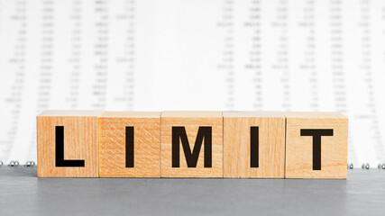 LIMIT word made with building blocks. Limit on wooden cubes on grey notepad. Business concept.