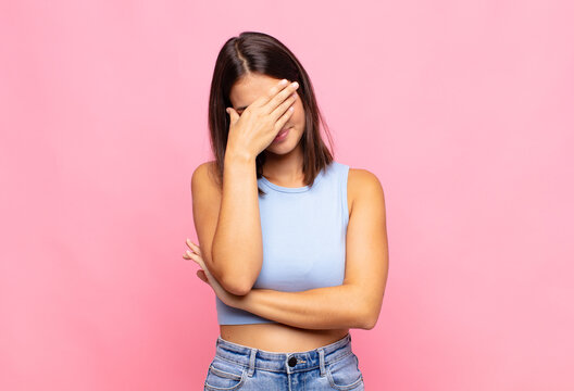 young pretty woman looking stressed, ashamed or upset, with a headache, covering face with hand