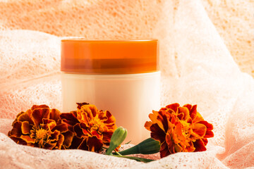 Concept of cosmetology and Spa procedures,  jar with cream and orange flowers, marigolds  on a light background. close-up