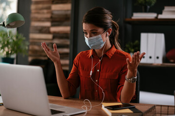 Beautiful businesswoman with medical mask working in office. Young businesswoman working on lap top...