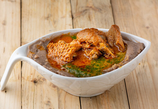 Amala with ewedu and beef stew in a white ceramic bowl on a wooden background