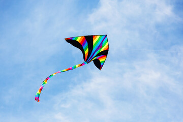 Colorful kite flying in the cloudy sky. Bright multicolored kite on a background of white clouds...