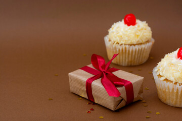 Gift boxes and vanilla cupcakes with cherry on top. Birthday concept. Sweet dessert with copy space.