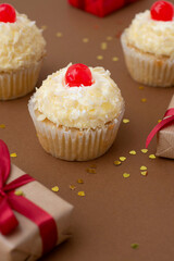 Cupcake with vanilla butter cream, brown background with gift boxes, birthday concept. Sweet dessert.