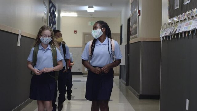 Primary and Elementary school children wear masks walking in the hall at school