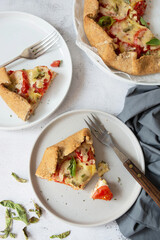 Slice of galette with tomatoes and cheese. Whole wheat rustic pie with tomatoes, cheeseand herbs. Healthy food concept.