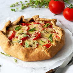 Homemade tomato tart or galette. Whole wheat rustic pie with tomatoes, cheeseand herbs. Square image.