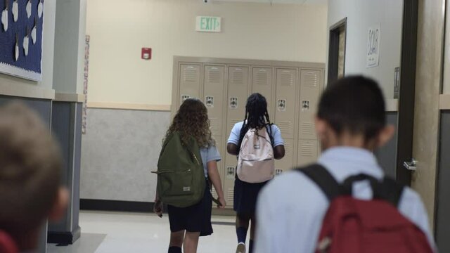 Diverse Primary and Elementary school children walk school hall in uniforms.