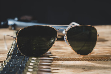 Sunglasses and ammunition in a close up shot with a pistol in background